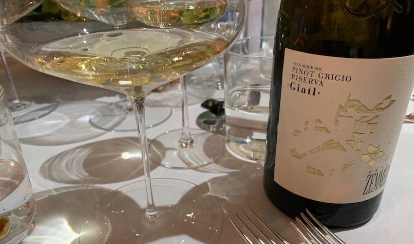 Peter Zemmer aus dem gleichnamigen Weingut erzeugt einige herausragende Riserva-Weine, darunter den Vigna Giatl Pinot Grigio, den Vigna Crivelli Chardonnay - Fein gedeckter Tisch mit weißer Tischdecke, mit Giatl-Flasche und Burgunderglas