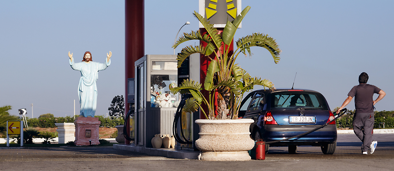 Übergroße Christusfigur aus Kunststoff am Rande einer Tankstelle in Apulien, Italien